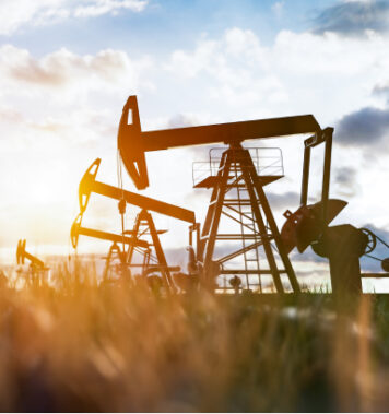 oil pump agricultural equipment in a field against a sunset in the battle river region