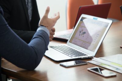 a BRAED office meeting with a closeup of a laptop open on a desk and an employee talking